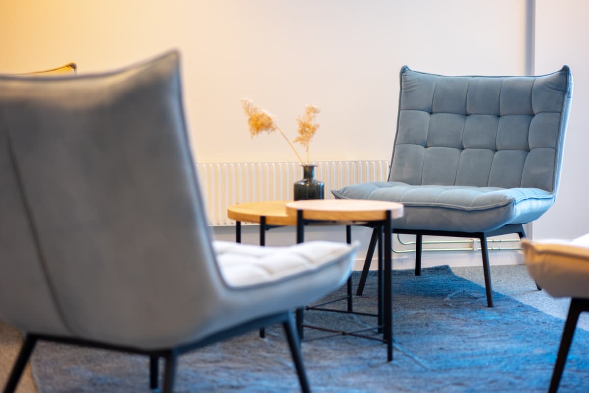 Ljust Mellan-kontor med grått golv, vita väggar och fönster mot grannt hus