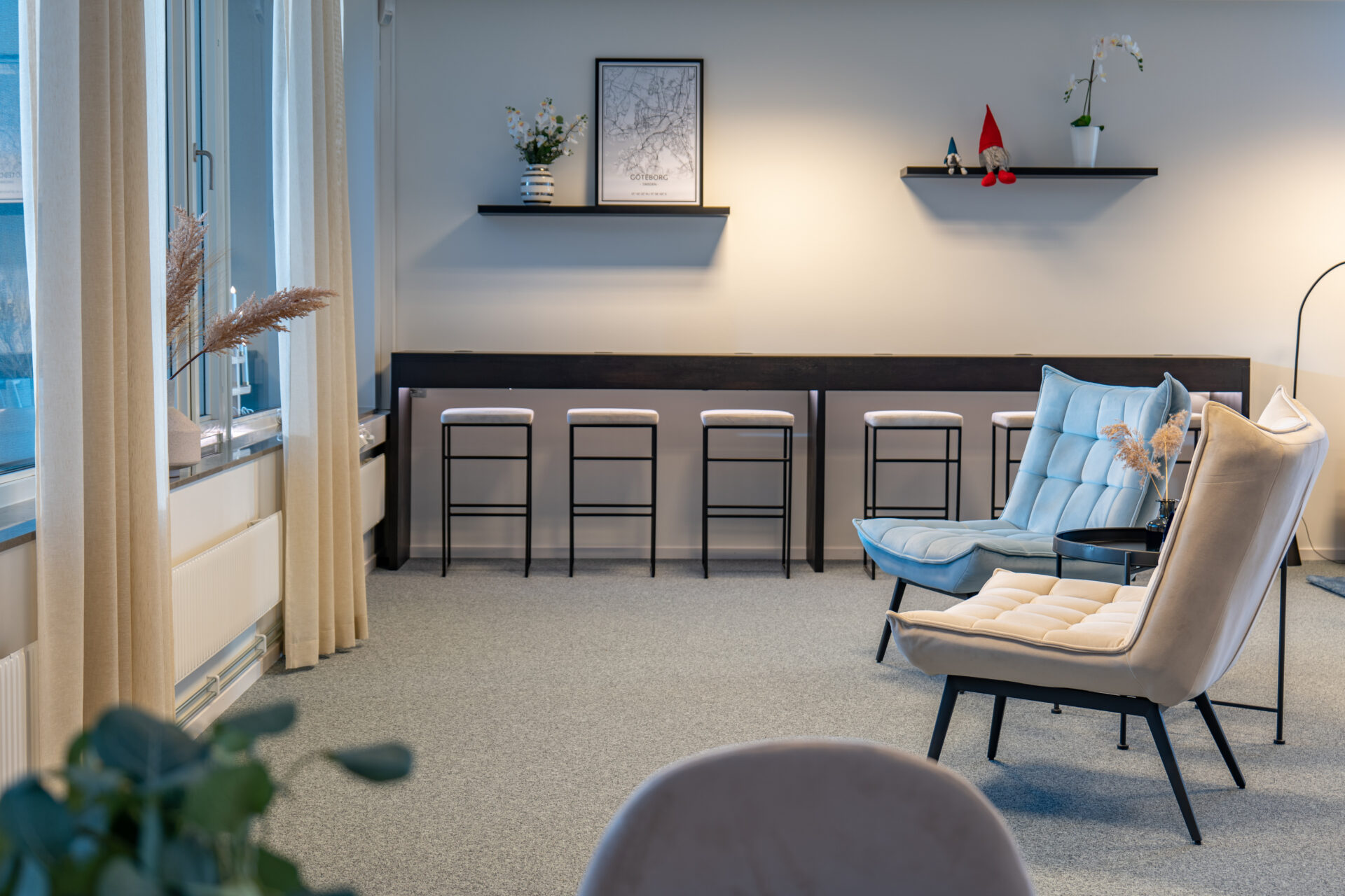 Modern lounge area at Seaside Office Hotels with Scandinavian interior, high stools, cozy armchairs, and Gothenburg wall art.