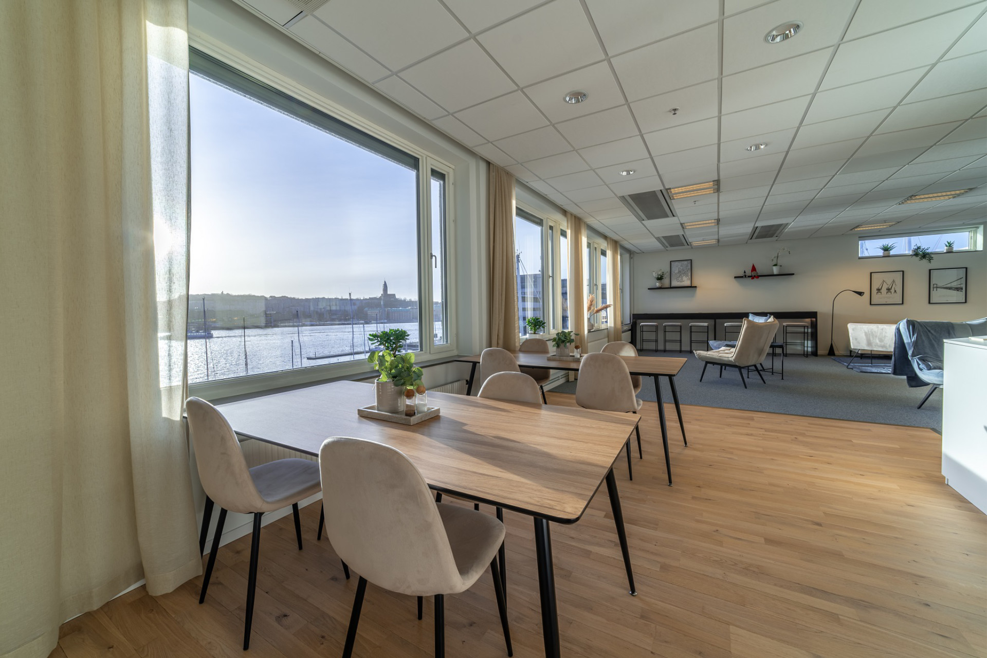 Bright lunchroom at Seaside Office Hotels with large windows, natural light, water views, and modern dining furniture.